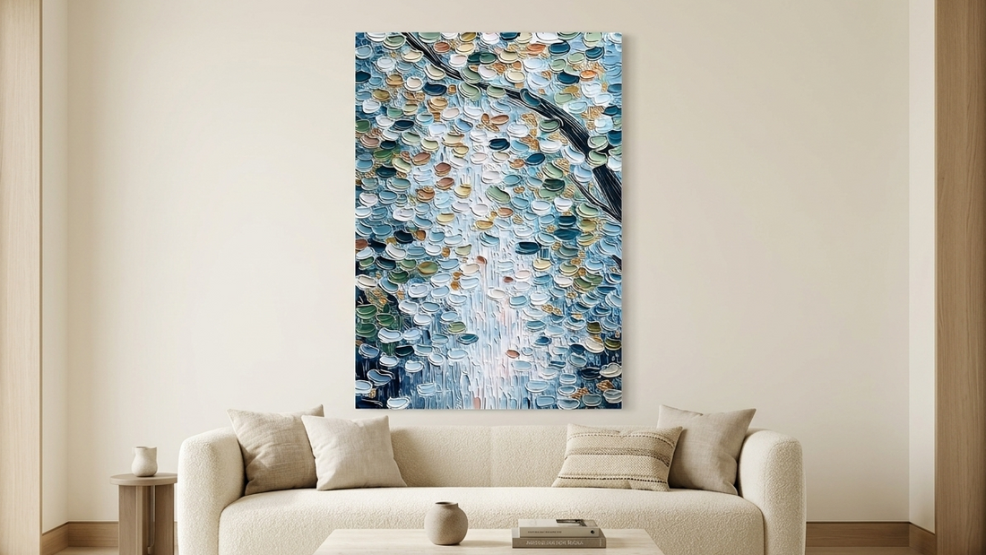 Blue textured impasto wall art displayed above a cream sofa in a modern organic living room interior.