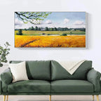 Golden Harvest landscape painting: golden field, farmhouse, path. Showcased above green sofa for modern living room decor.