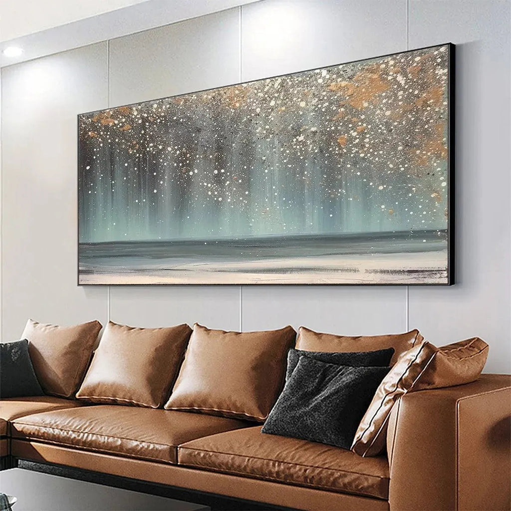 AURORA DUST: Textured abstract ocean painting with gold speckles above a brown leather sofa in a modern living room.