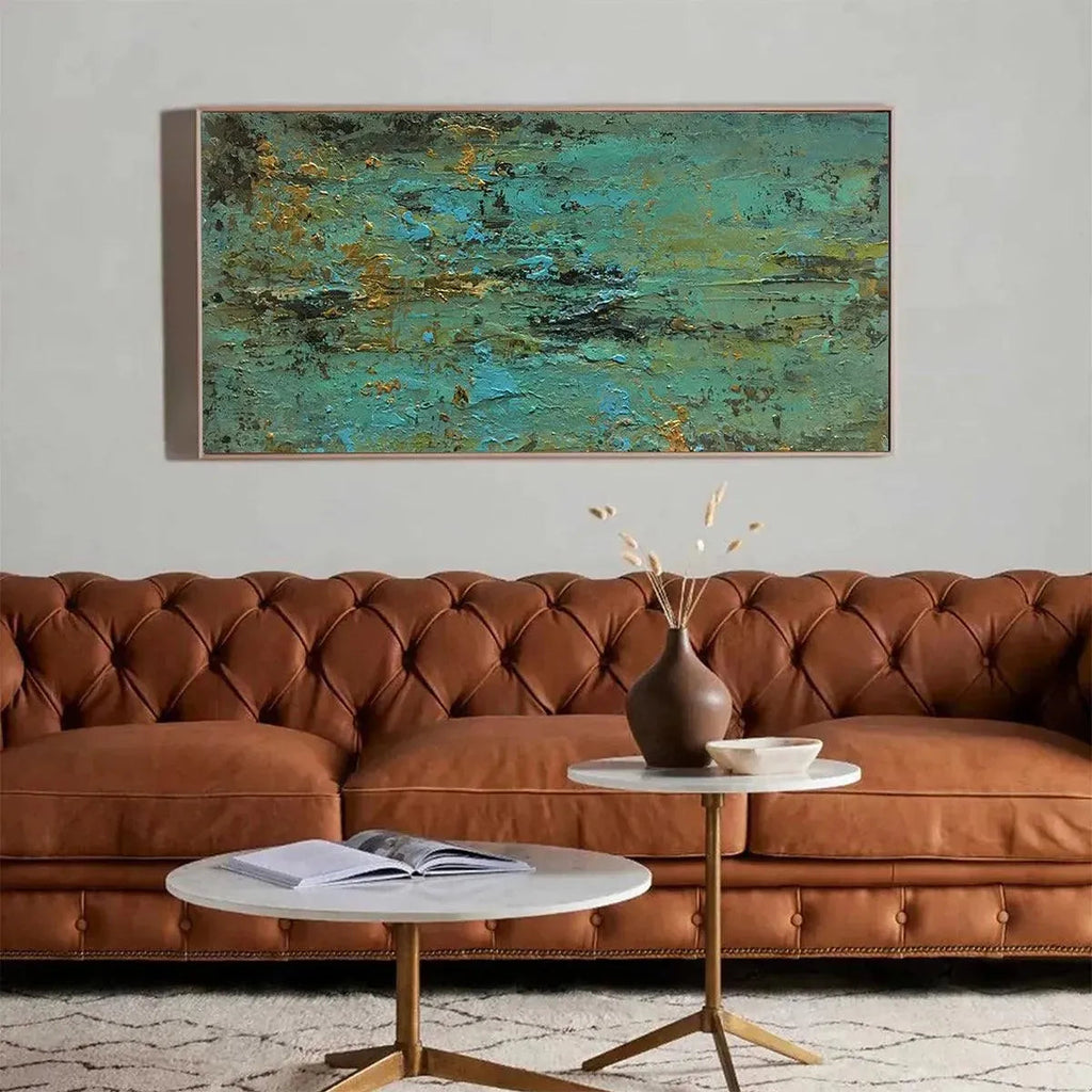 Golden Tide abstract painting in teal and gold, above brown leather sofa in living room.