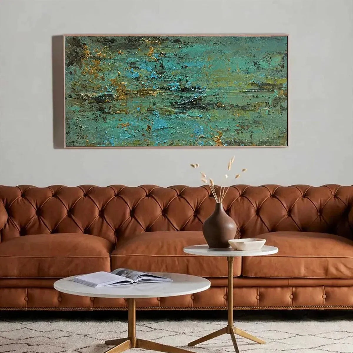 Golden Tide abstract painting in teal and gold, above brown leather sofa in living room.