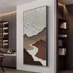 EARTH RIVER textured vertical painting: Brown mountains with white peaks and a winding river, displayed in a modern home.