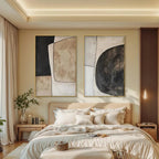 Two vertical abstract geometric paintings in black, beige, and white with gold frames above a bed.