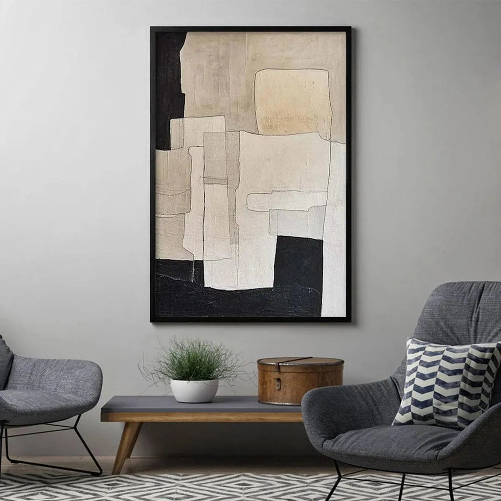 Framed beige and black abstract painting by Javier Ramirez in a modern living room with grey chairs.