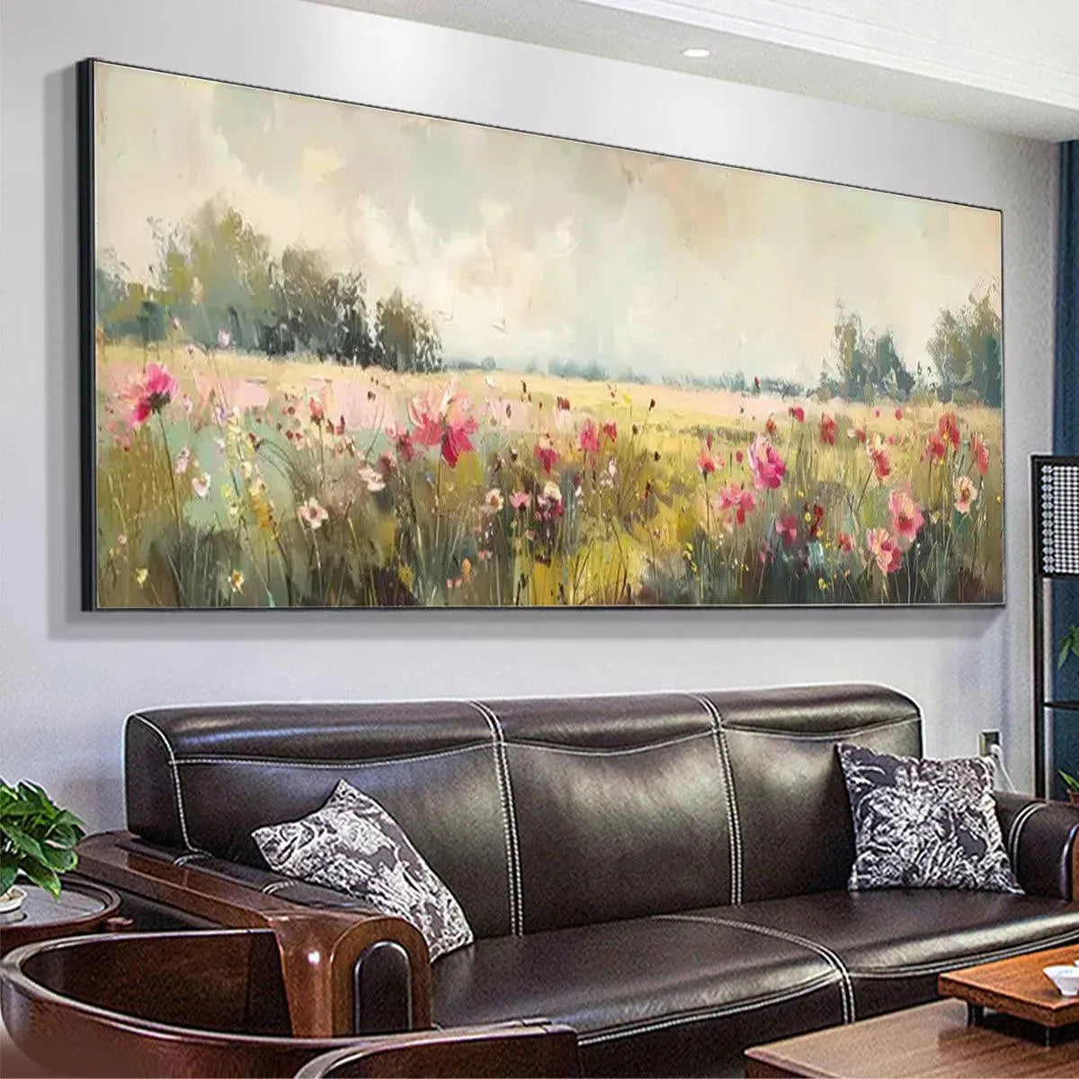 Panoramic impressionist painting of a wildflower field with pink flowers above a brown leather sofa.