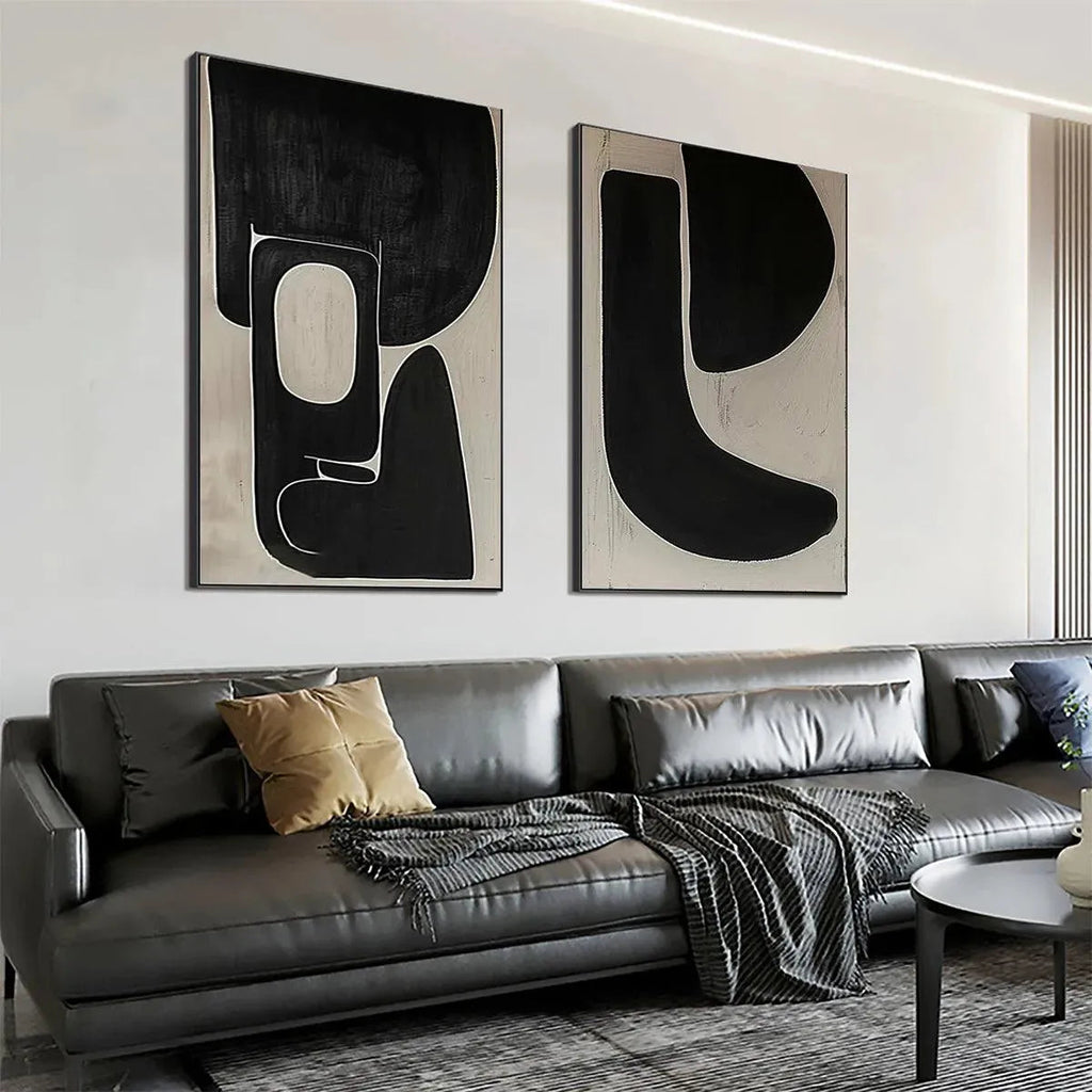 Set of 2 black and beige abstract vertical paintings by Javier Ramirez, displayed above a grey sofa.