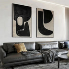 Set of 2 black and beige abstract vertical paintings by Javier Ramirez, displayed above a grey sofa.