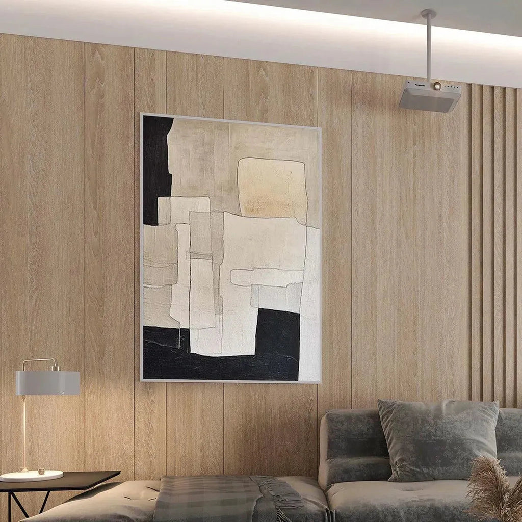 Minimalist abstract painting in beige and black geometric shapes by Javier Ramirez in a modern living room setting.