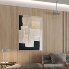 Minimalist abstract painting in beige and black geometric shapes by Javier Ramirez in a modern living room setting.