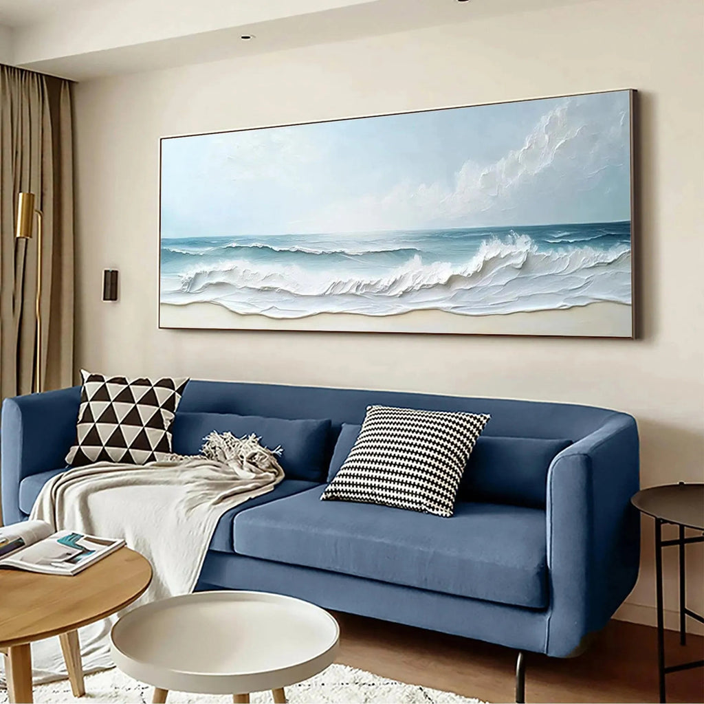 Liam O'Connell "Ocean Waves Panoramic" painting displayed above a blue sofa in a living room setting.