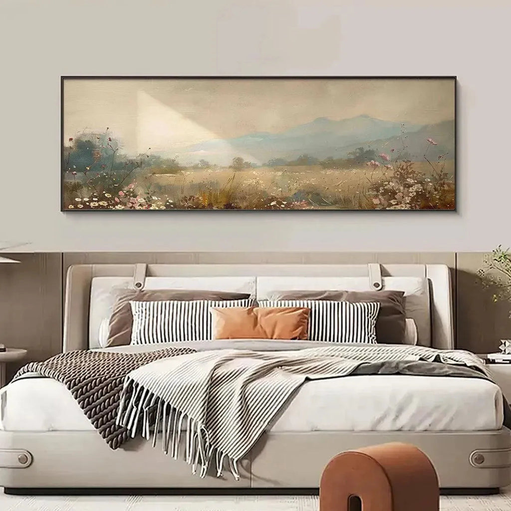 Liam O'Connell's Meadow Valley panoramic painting above bed in a bedroom. Sunlit field, wildflowers, misty mountains.