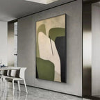 Vertical minimalist abstract painting with organic shapes in olive green, cream, and black, shown in a modern room.