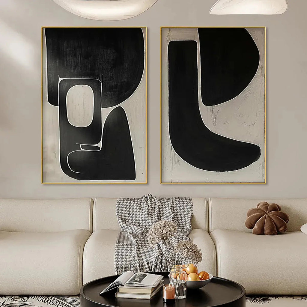 Black & Beige Abstract Diptych II set of 2 vertical wall art by Javier Ramirez in gold frames above sofa.