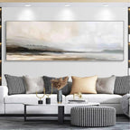 Liam O'Connell's panoramic misty mountain lake landscape painting in muted earth tones above a white sofa.