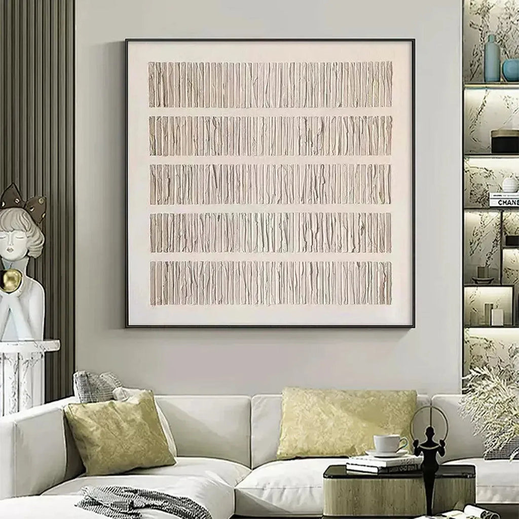 Minimalist textured beige painting with five horizontal rows of vertical lines in black frame, styled above white sofa.